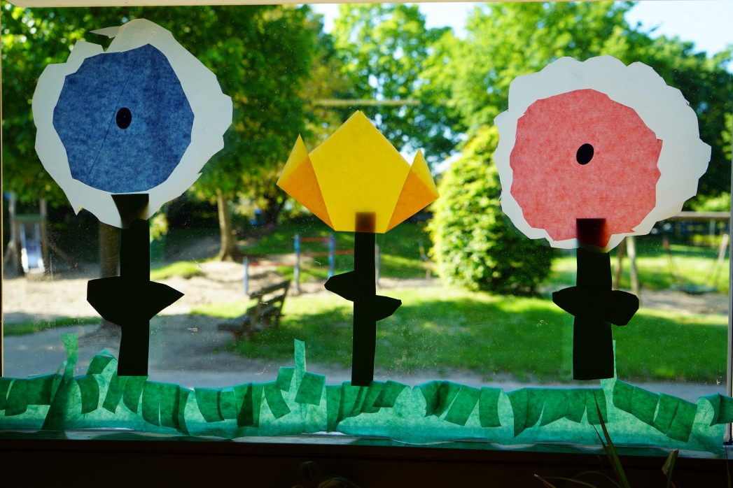 Die Kinder haben mit Transparentpapier eine bunte Blumenwiese für das Fenster gestaltet