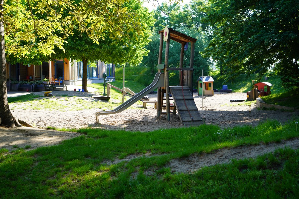 Unser weitläufiges und hügeliges Außengelände mit unterschiedlichen Spielmöglichkeiten, wie Rutschenturm und Wassermatschanlage